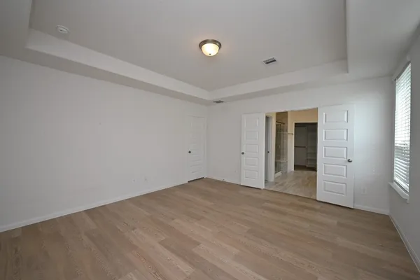 a view of an empty room with window and wooden floor