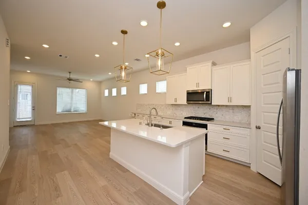 a large kitchen with stainless steel appliances granite countertop a lot of counter space and wooden floor