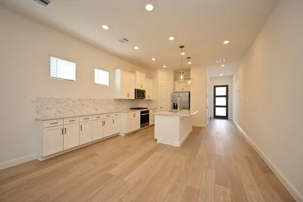 a large kitchen with stainless steel appliances lots of counter space and a sink