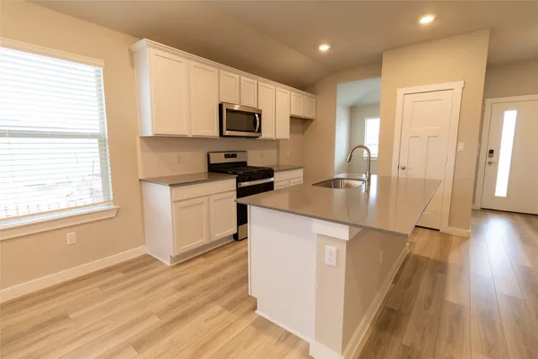 a kitchen with granite countertop a sink appliances cabinets and a counter top space