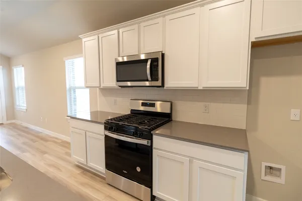 a kitchen with white cabinets and black appliances