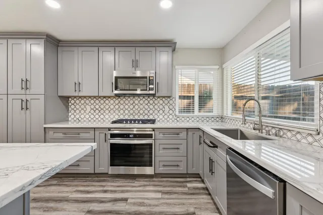 a large kitchen with stainless steel appliances granite countertop a large counter top a sink and a refrigerator