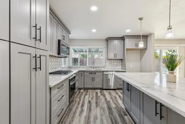 a kitchen with kitchen island granite countertop a sink appliances cabinets and counter space