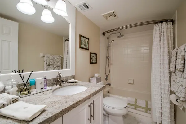 a bathroom with a granite countertop sink toilet and shower