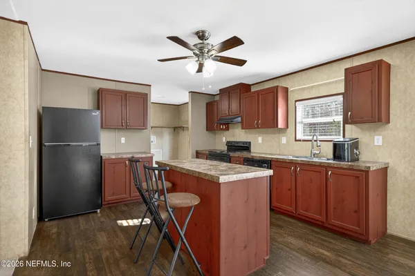 a kitchen with stainless steel appliances granite countertop a refrigerator a sink dishwasher a stove with wooden cabinets and floor