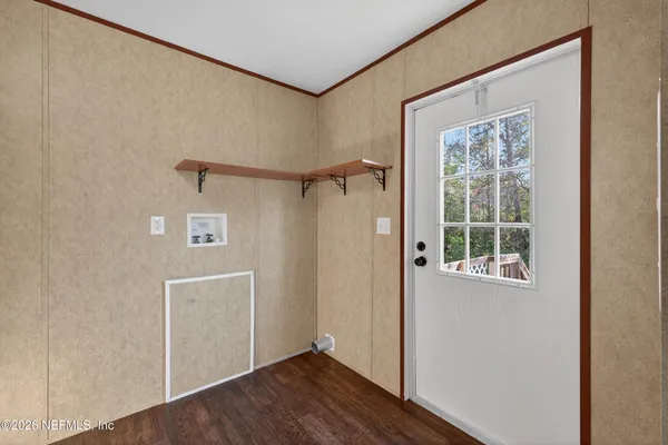 a view of an empty room with wooden floor and a window