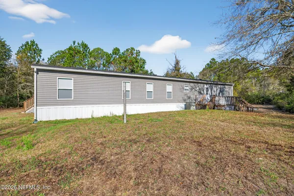 a front view of house with yard and trees in the background