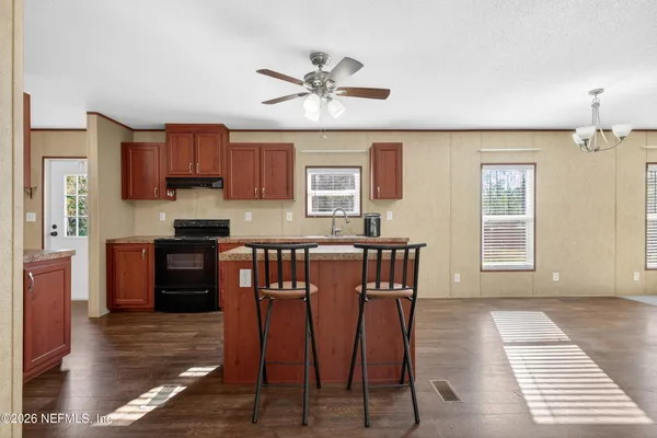 a kitchen with stainless steel appliances granite countertop a stove a sink dishwasher and a refrigerator with wooden floor