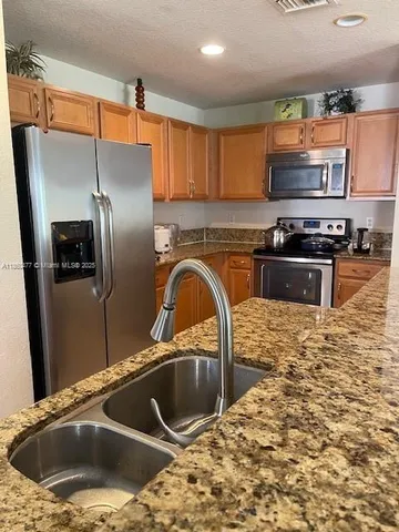 a kitchen with stainless steel appliances granite countertop a sink a refrigerator and a stove