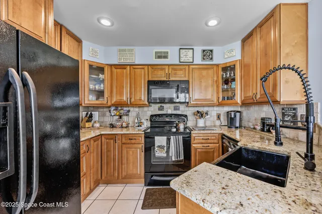 a kitchen view with stainless steel appliances kitchen island granite countertop a refrigerator and a stove top oven