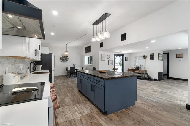 a large kitchen with stainless steel appliances granite countertop a stove and a wooden floors