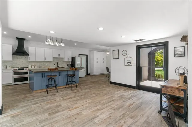 a living room with stainless steel appliances kitchen island granite countertop furniture and a wooden floor