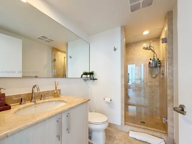 a bathroom with a granite countertop sink toilet and shower