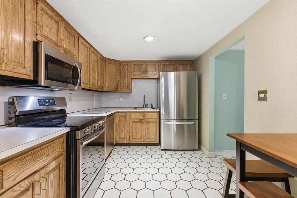 3 Spruce Street Stoneham, MA 02180 - Photo 15 of 38 a kitchen with a sink a microwave a refrigerator and cabinets