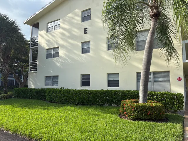 a view of a white house with a yard and potted plants