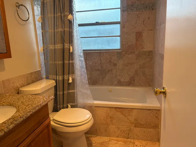 a bathroom with a granite countertop toilet sink and mirror
