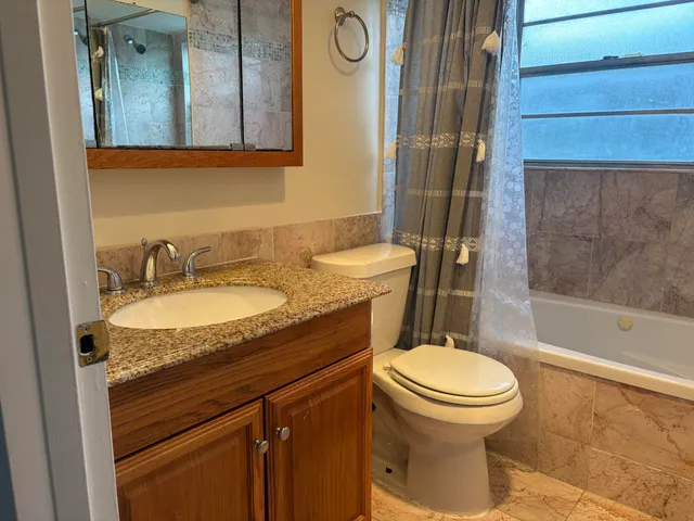 a bathroom with a granite countertop toilet sink and mirror