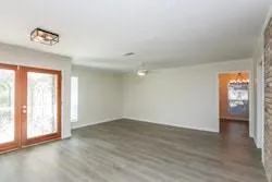 a view of an empty room with wooden floor fireplace and a window