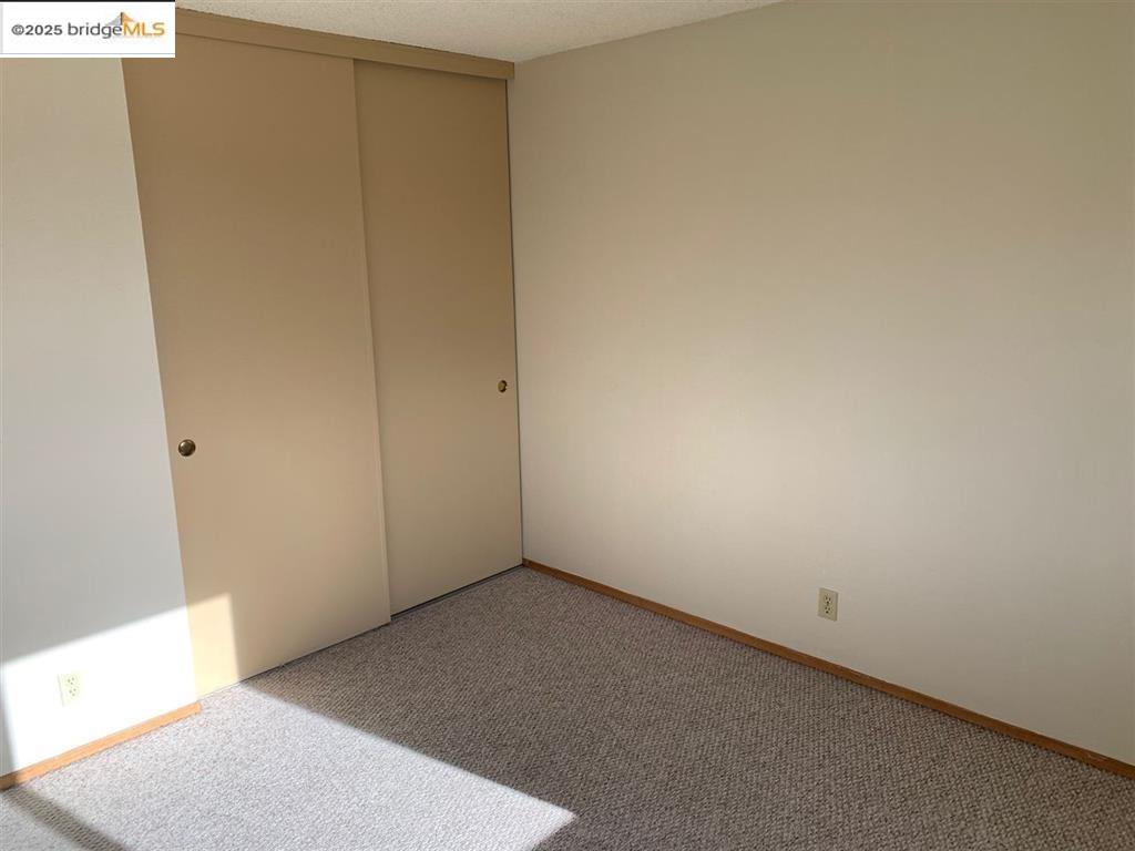708 Solano Avenue, Unit D Albany, CA 94706 - Photo 18 of 23 Unfurnished bedroom featuring carpet, a closet, and a textured ceiling
