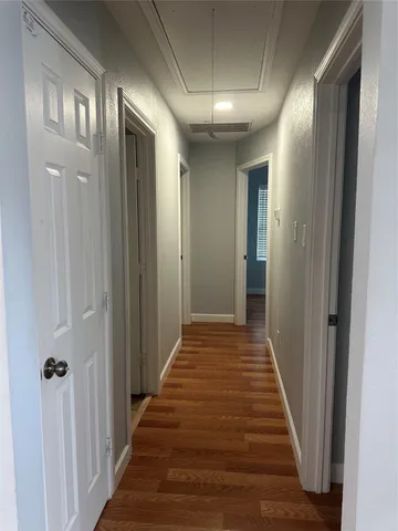 a view of a hallway with wooden floor and a bathroom