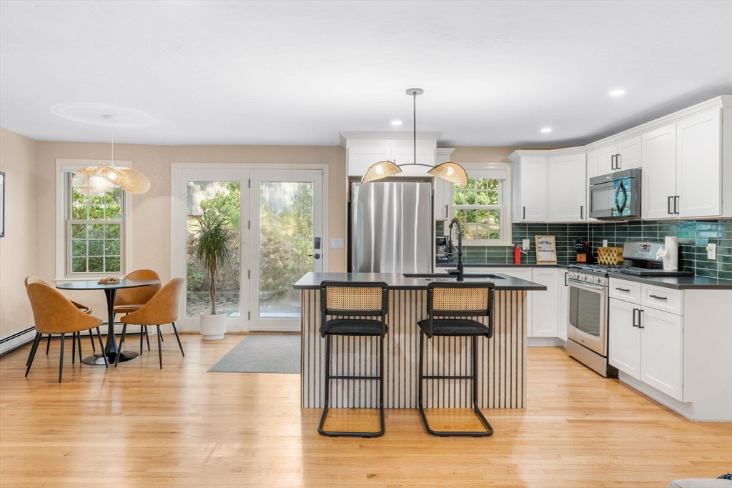 7 Hunter's Trail Sandwich, MA 02563 - Photo 13 of 27 a kitchen with stainless steel appliances granite countertop a stove top oven a sink a dining table and chairs with wooden floor