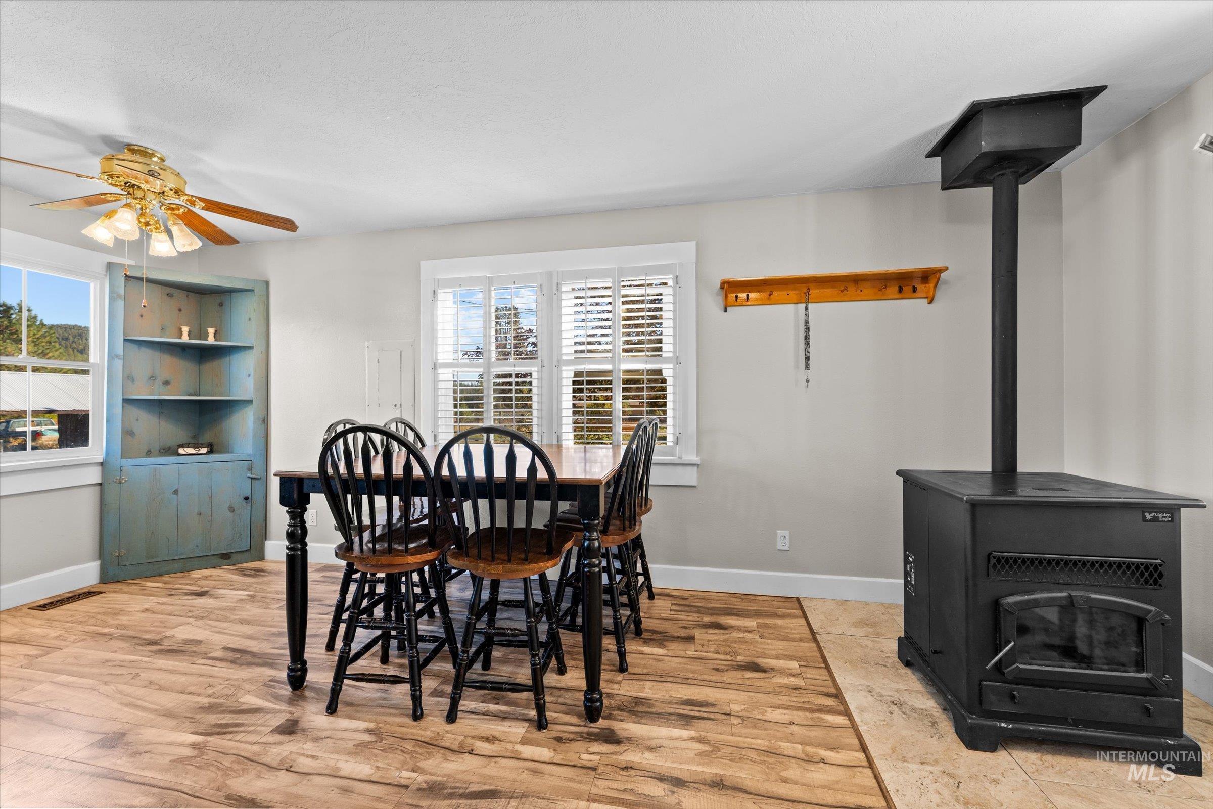 315 South Middlefork Road Garden Valley, ID 83622 - Photo 17 of 49 Dining room featuring a wood stove, light wood-style flooring, and ceiling fan