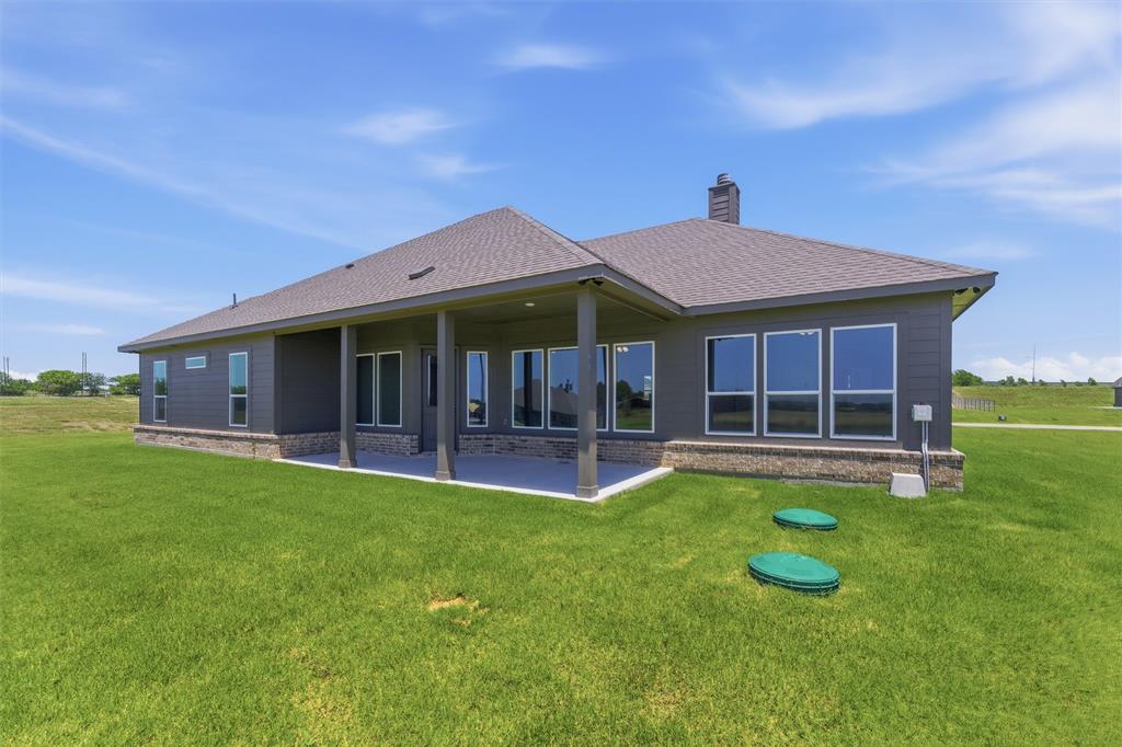 114 Hillview Trail Decatur, TX 76234 - Photo 24 of 27 Exterior featuring dark gray siding, a covered patio with columns, a shingled roof, a brick foundation perimeter, and multiple large windows