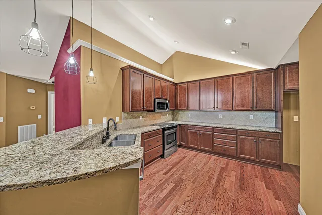a large kitchen with granite countertop a large counter top space appliances and cabinets