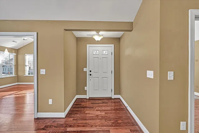 a view of a hallway with wooden floor and a living room