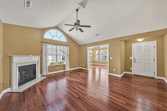 a view of an empty room with window and wooden floor