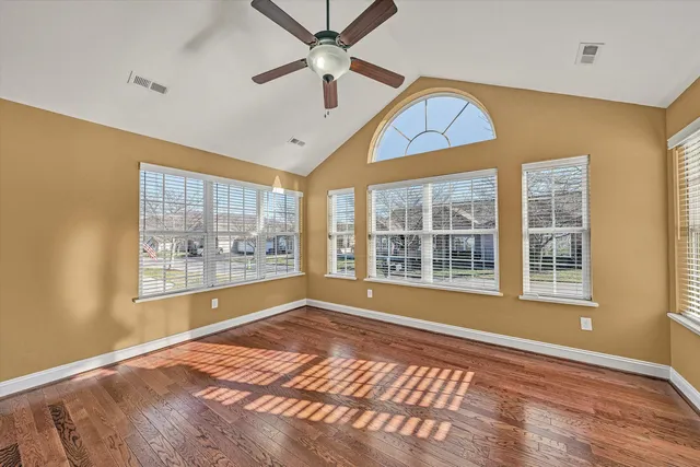 a view of an empty room with a window and wooden floor