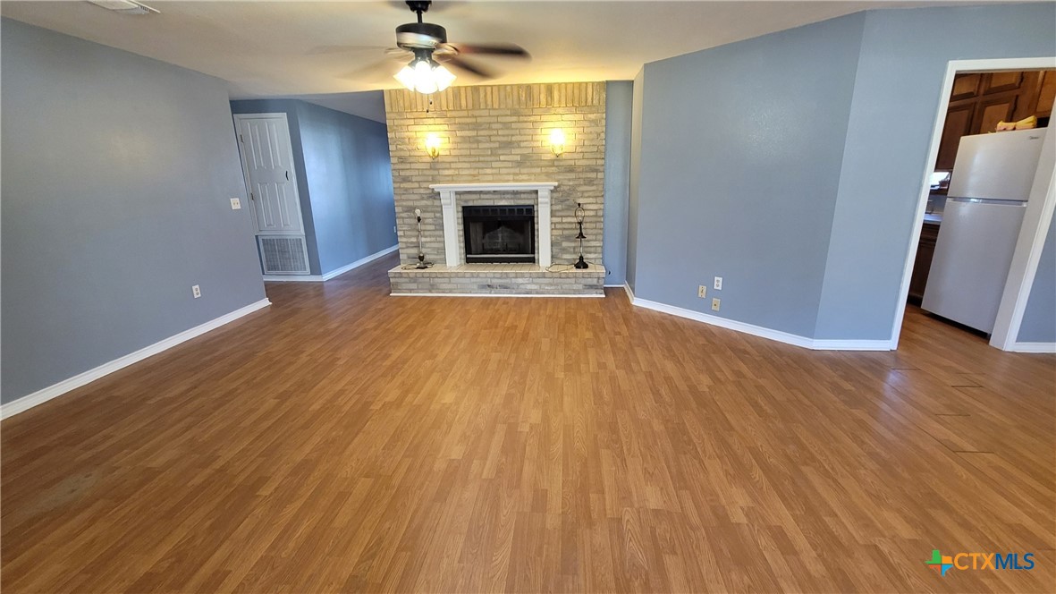 127-129 McAdams Road Goliad, TX 77963 - Photo 16 of 33 an empty room with wooden floor fireplace and windows