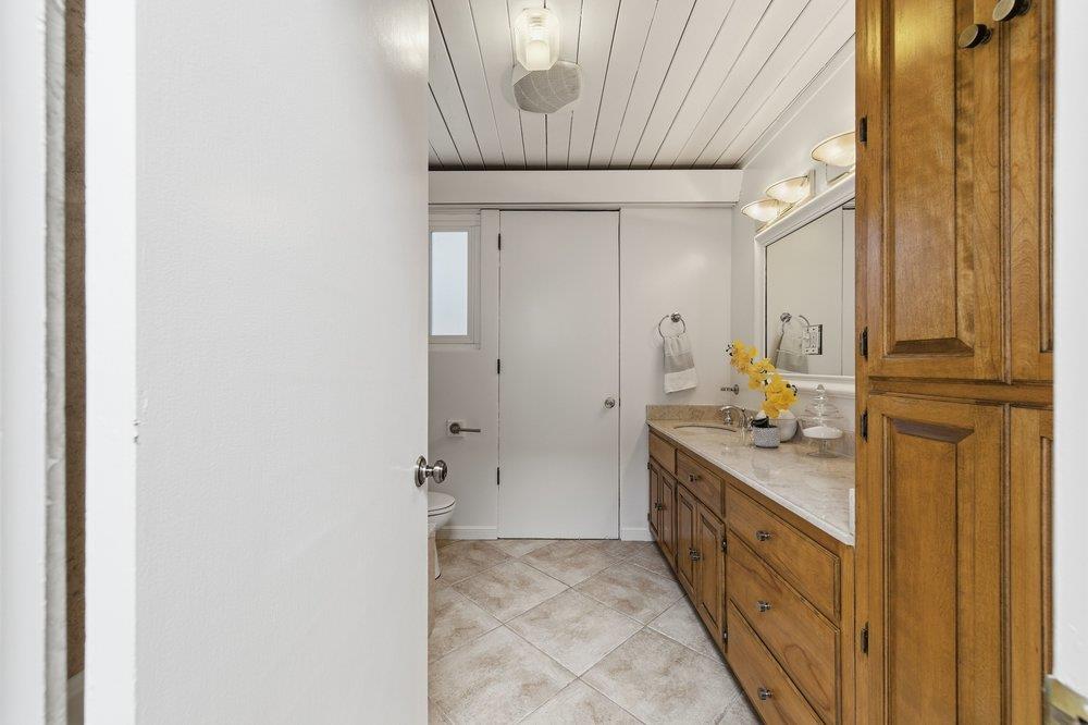 2203 Allegheny Way San Mateo, CA 94402 - Photo 16 of 56 a bathroom with a granite countertop sink a mirror and a shower