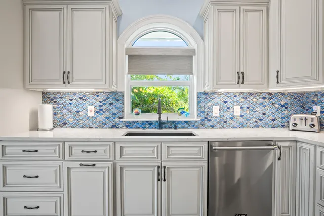 a kitchen with stainless steel appliances granite countertop a dining table chairs refrigerator and sink