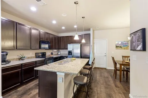 a kitchen with stainless steel appliances granite countertop a sink a stove a refrigerator cabinets and chairs