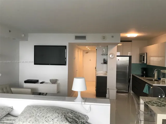 a living room with stainless steel appliances furniture and a flat screen tv