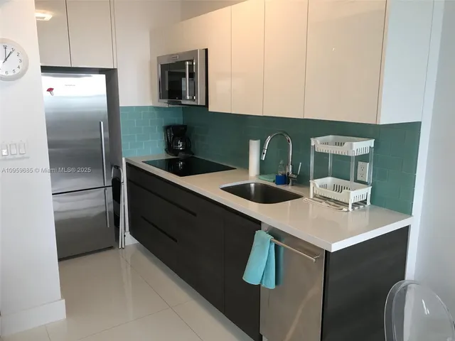 a kitchen with stainless steel appliances granite countertop a sink a refrigerator and a stove