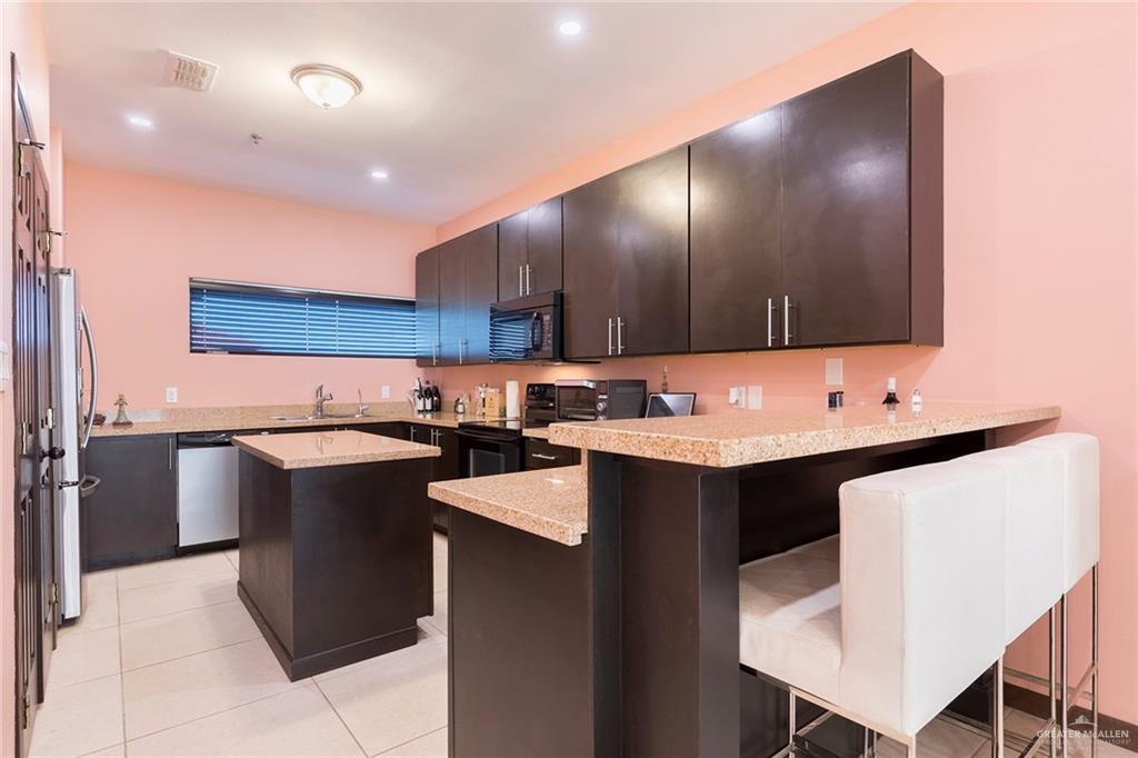 813 Travis Street, Unit 416 Mission, TX 78572 - Photo 8 of 32 a kitchen with a sink refrigerator and cabinets