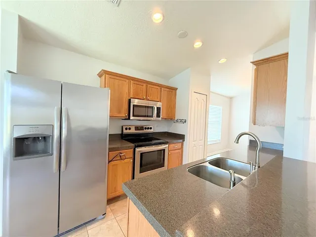 a kitchen with stainless steel appliances granite countertop a sink a stove a refrigerator a washer and dryer