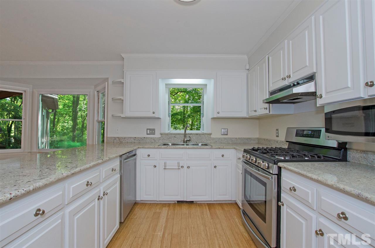 6205 Lookout Loop Raleigh, NC 27612 - Photo 5 of 25 a kitchen with granite countertop a sink cabinets wooden floor and stainless steel appliances