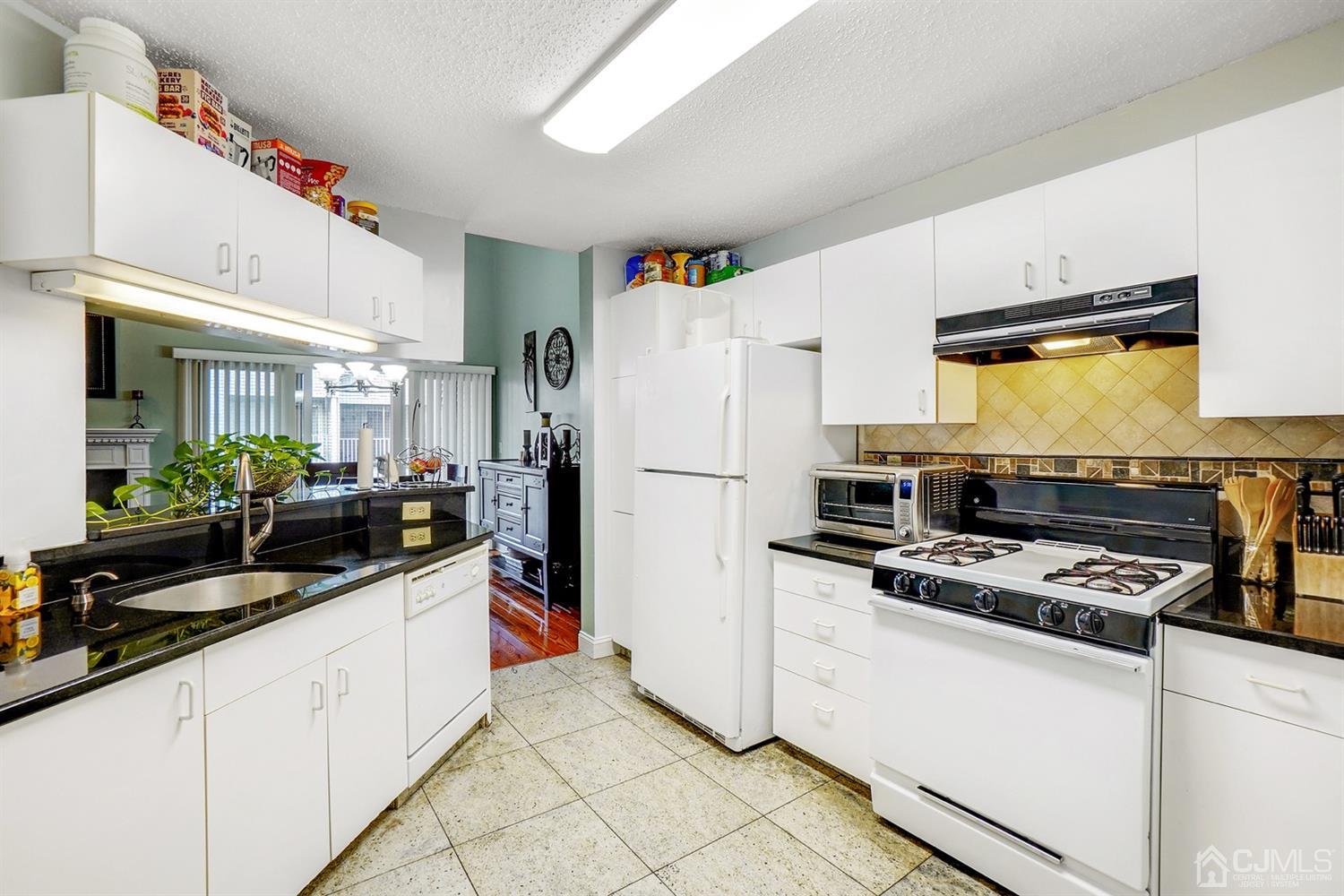 934 Edpas Road New Brunswick, NJ 08901 - Photo 7 of 16 a kitchen with granite countertop a refrigerator a stove a sink a counter space and cabinets