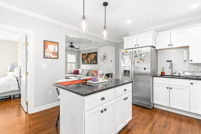 a kitchen with stainless steel appliances granite countertop a refrigerator a sink dishwasher and white cabinets with wooden floor