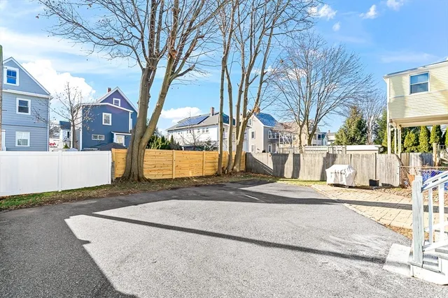 a view of a white house next to a road and yard