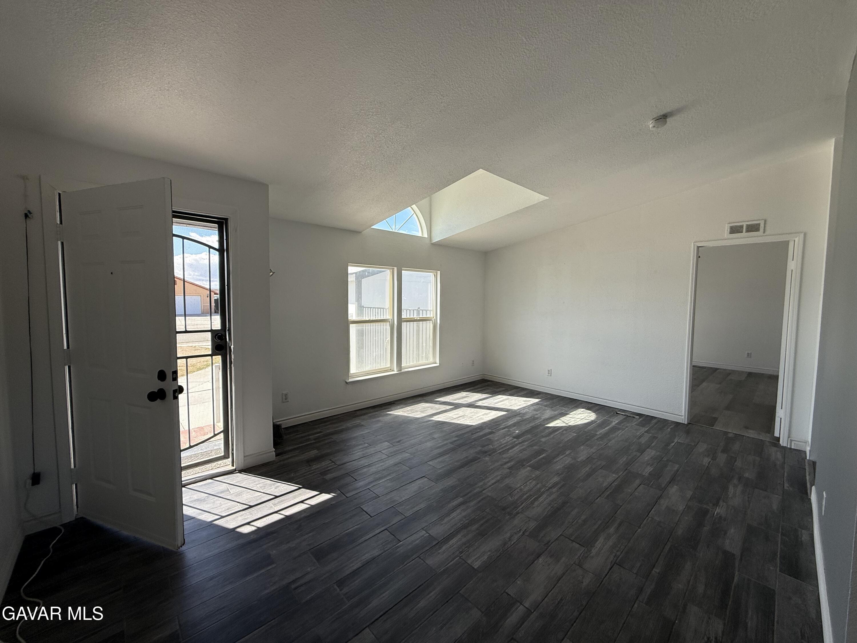 1365 Richfield Avenue Rosamond, CA 93560 - Photo 2 of 17 an empty room with wooden floor and windows