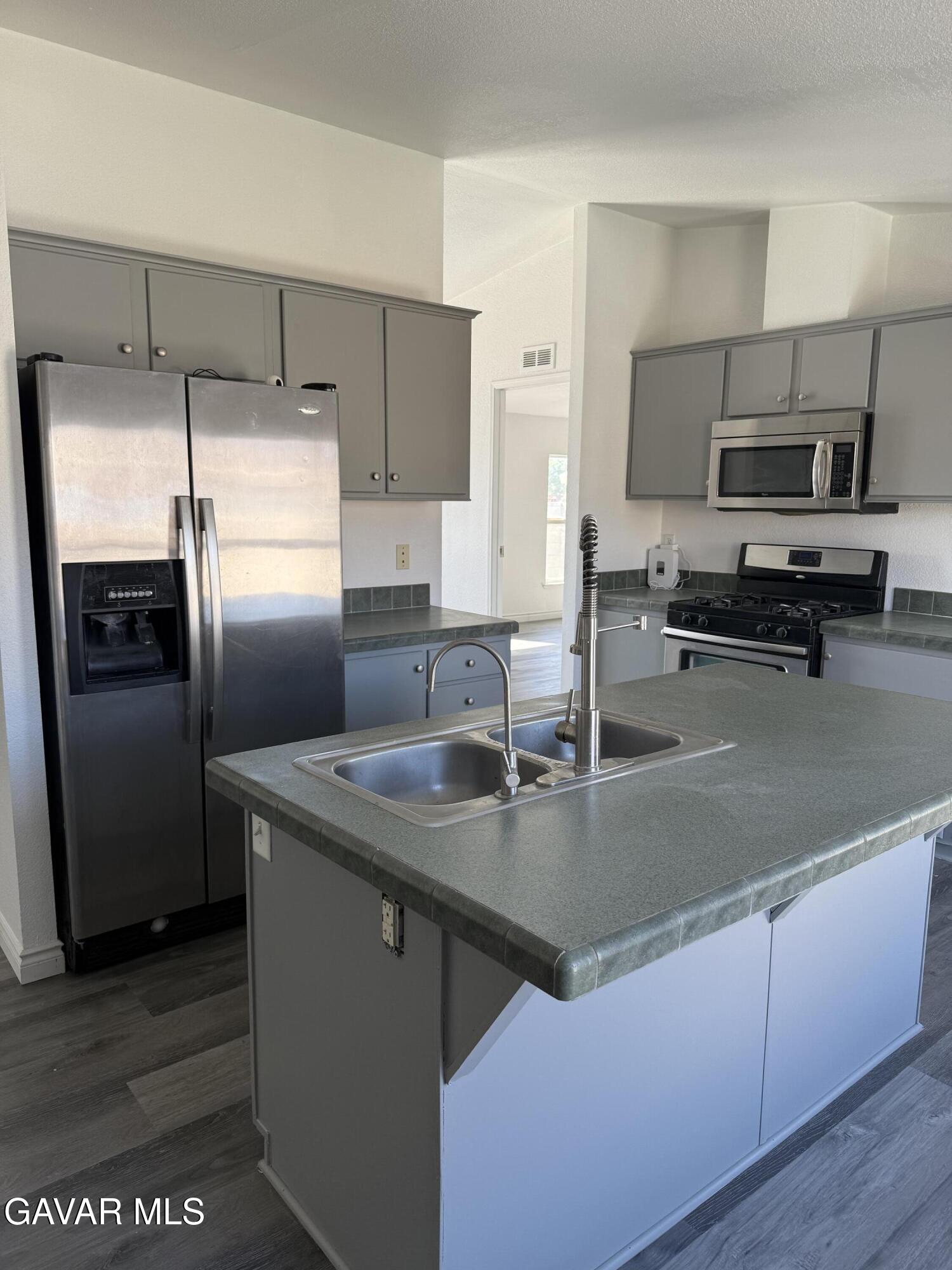 1365 Richfield Avenue Rosamond, CA 93560 - Photo 4 of 17 a kitchen with stainless steel appliances granite countertop a sink a stove and a refrigerator