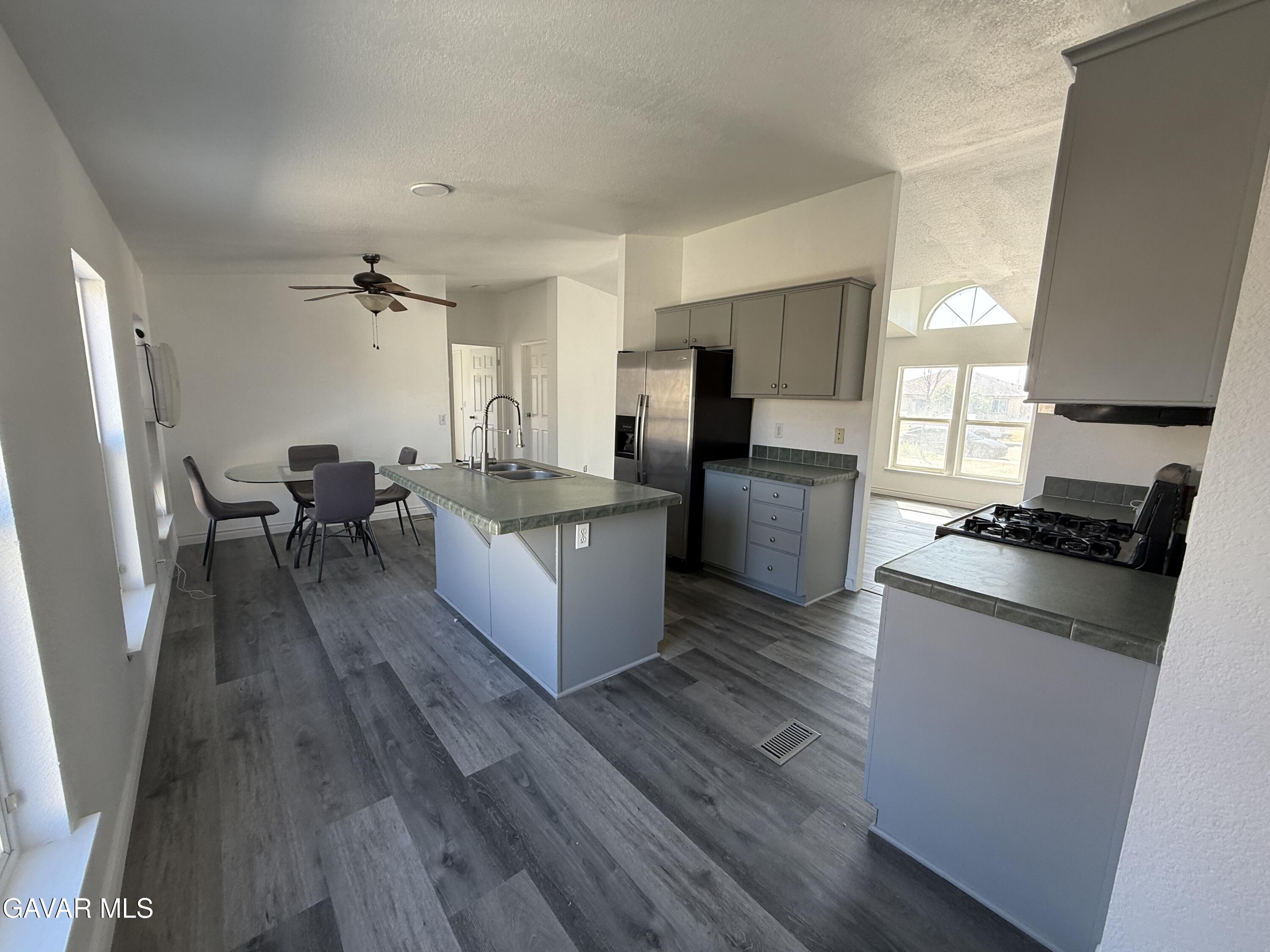 1365 Richfield Avenue Rosamond, CA 93560 - Photo 5 of 17 a large kitchen with a table chairs refrigerator and wooden floor