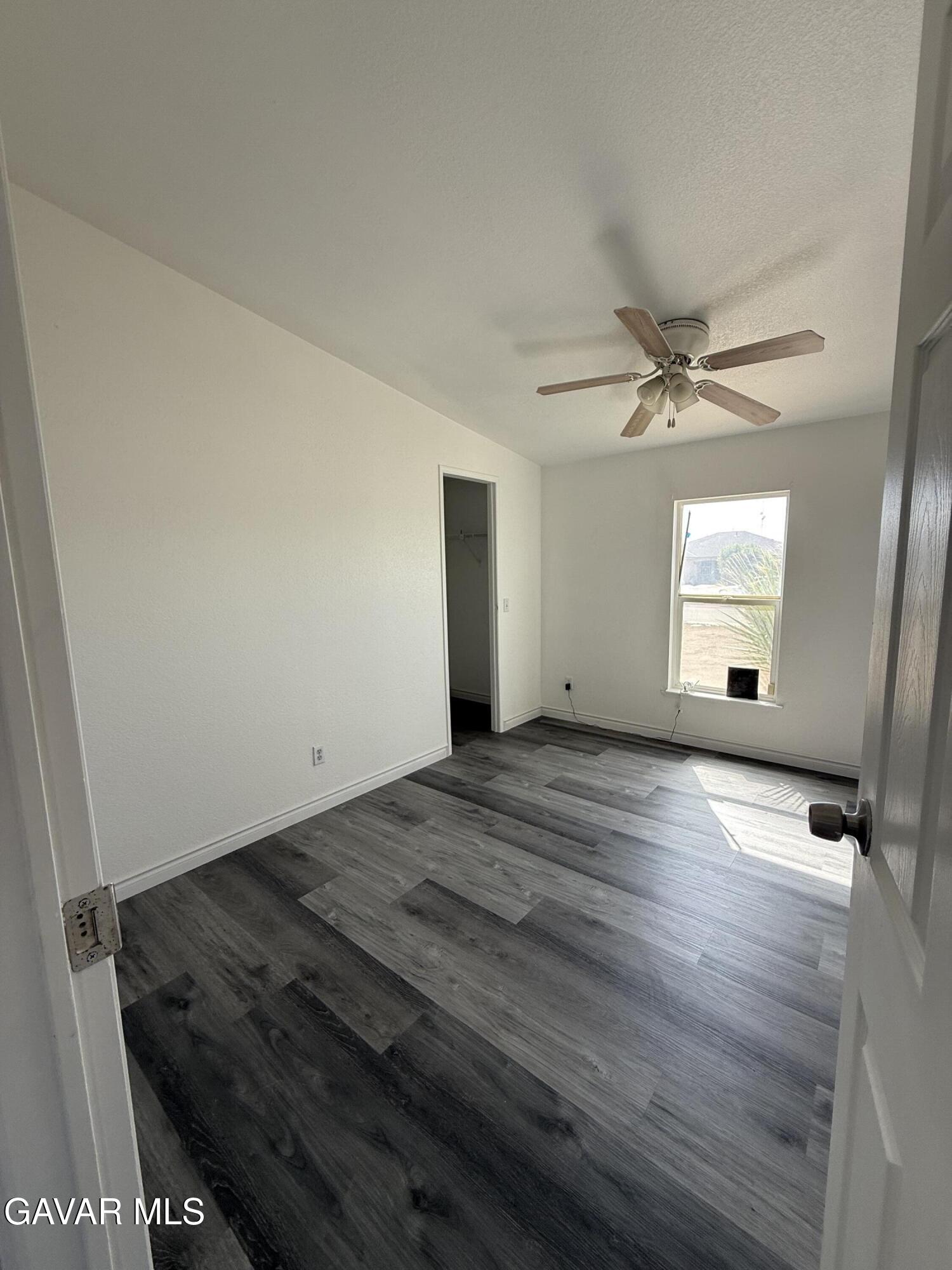 1365 Richfield Avenue Rosamond, CA 93560 - Photo 7 of 17 an empty room with wooden floor fan and windows
