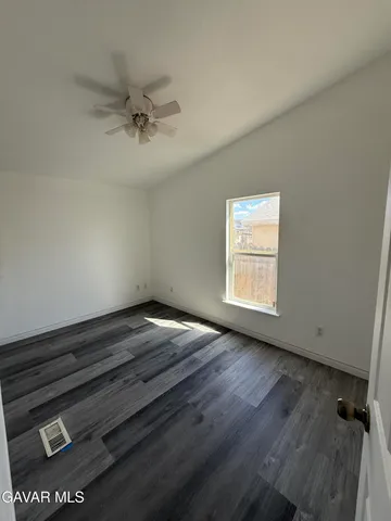 an empty room with wooden floor cabinet and windows