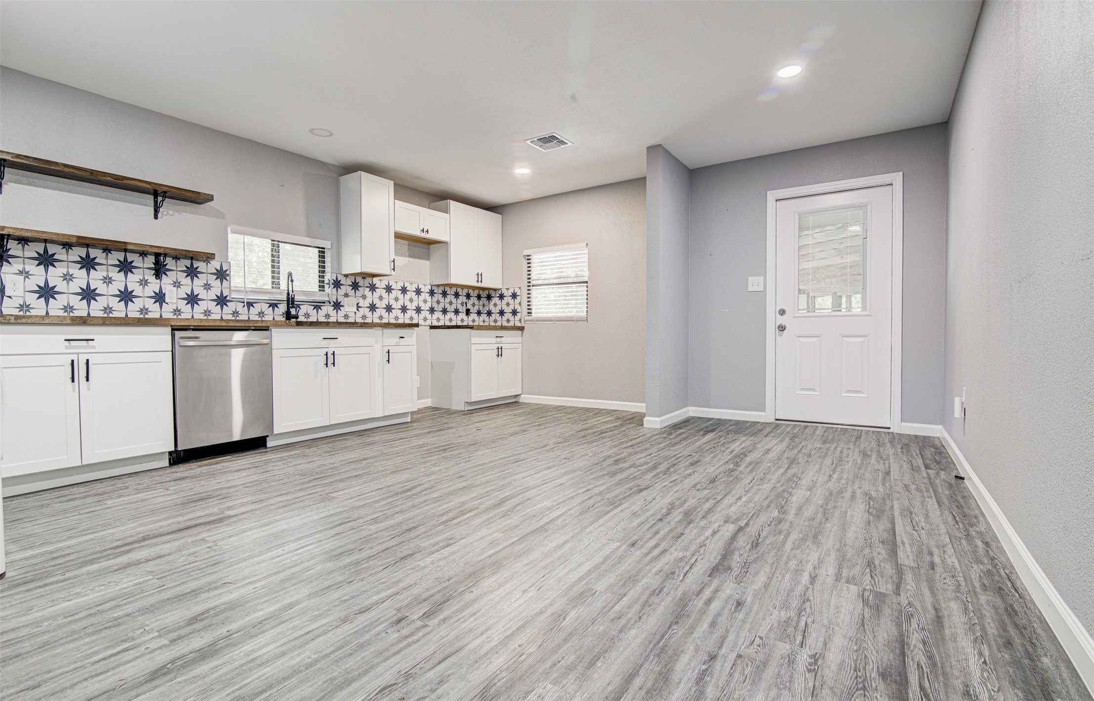 1807 San Jose Street Georgetown, TX 78626 - Photo 5 of 21 A clean, modern kitchen area showcasing bright white cabinetry, stylish tiled backsplash, and resilient flooring.