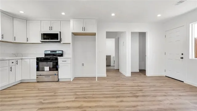 a view of kitchen with stainless steel appliances refrigerator stove microwave and cabinets